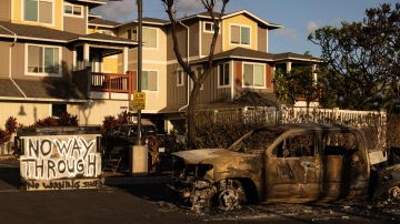 A burnt out car and a sign reading "No Way Through" stand in the driveway of charred apartment complex in the aftermath of a wildfire in Lahaina, western Maui, Hawaii on August 12, 2023. Hawaii's Attorney General, Anne Lopez, said August 11, she was opening a probe into the handling of devastating wildfires that killed at least 80 people in the state this week, as criticism grows of the official response. The announcement and increased death toll came as residents of Lahaina were allowed back into the town for the first time. (Photo by Yuki IWAMURA / AFP) (Photo by YUKI IWAMURA/AFP via Getty Images)