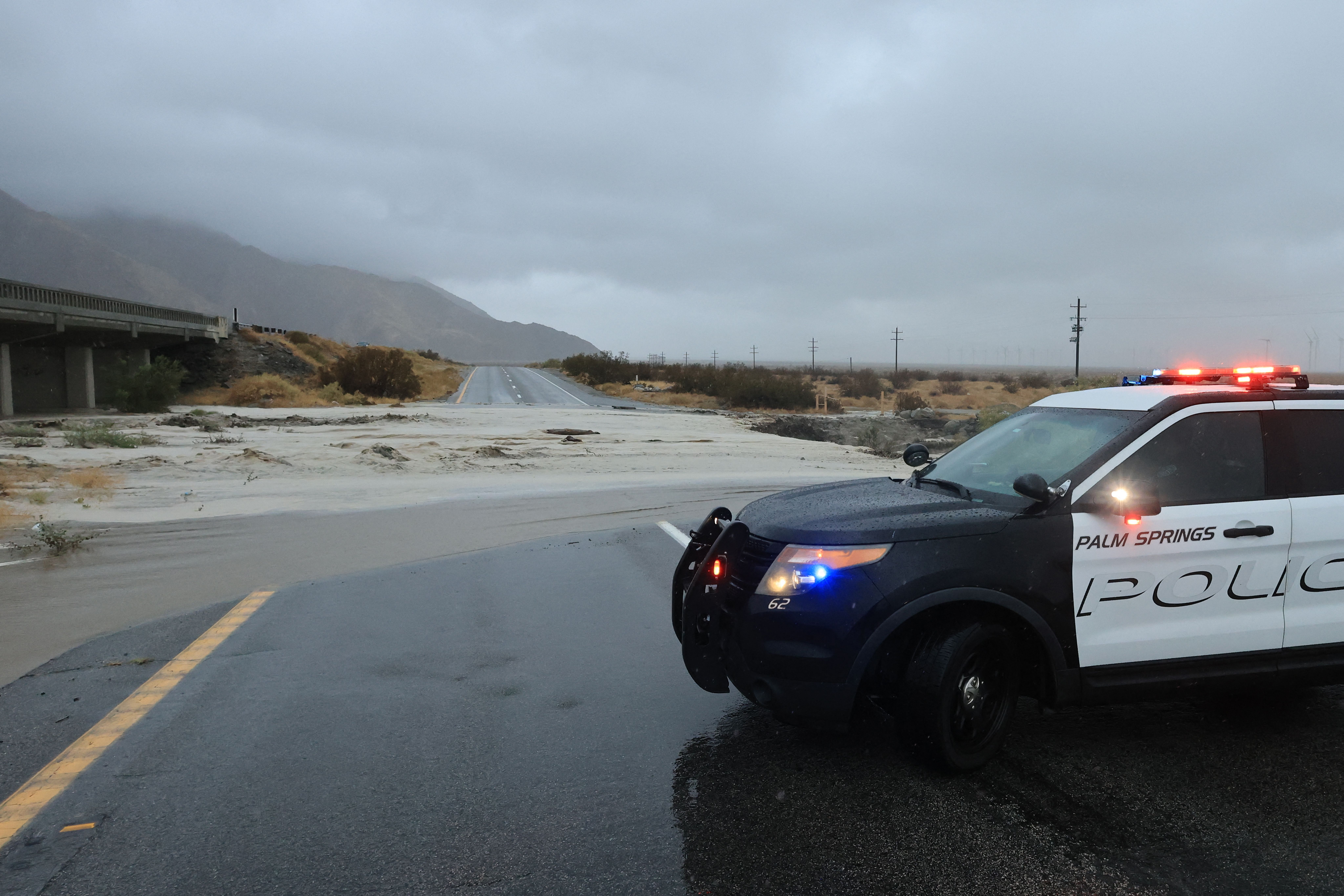 A police car blocks a washed out road as Tropical Storm Hilary heads north into Palm Springs, California, on August 20, 2023. Heavy rains lashed California as Tropical Storm Hilary raced in from Mexico, bringing warnings of potentially life-threatening flooding in the typically arid southwestern United States. (Photo by DAVID SWANSON / AFP) (Photo by DAVID SWANSON/AFP via Getty Images)