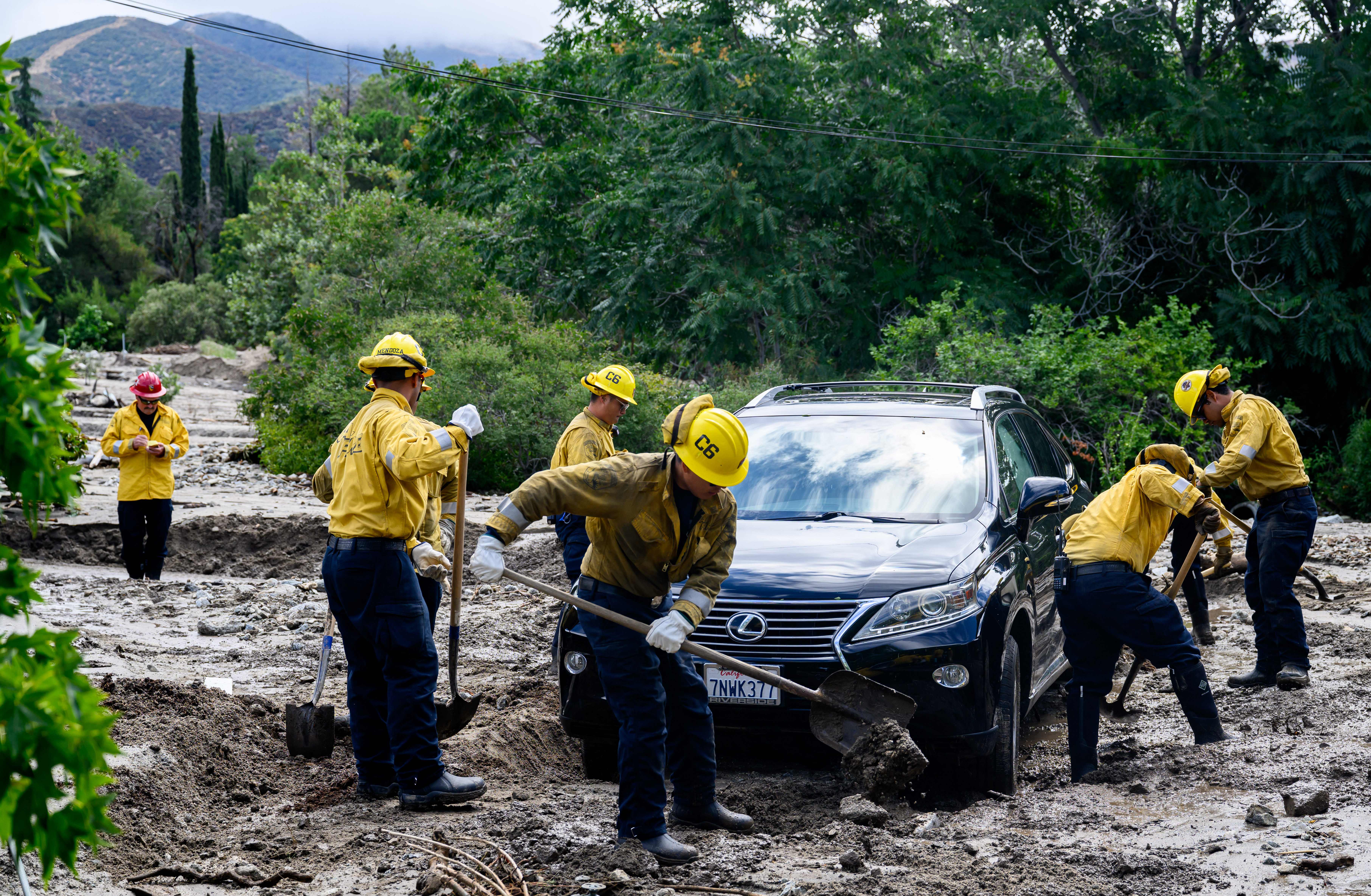 CalFire firefighters help clear mud and debris for residents stuck in their home in Yucaipa, California on August, 21, 2023. Tropical Storm Hilary drenched Southern California with record rainfall, shutting down schools, roads and businesses before edging in on Nevada on August 21, 2023. California Governor Gavin Newsom had declared a state of emergency over much of the typically dry area, where flash flood warnings remained in effect until this morning.  (Photo by JOSH EDELSON / AFP) (Photo by JOSH EDELSON/AFP via Getty Images)