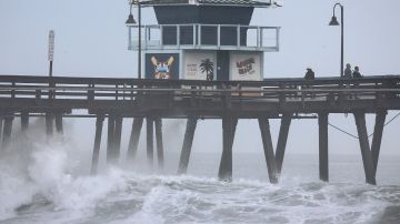 IMPERIAL BEACH, CALIFORNIA - AUGUST 20: People stand on a pier over the Pacific Ocean with Tropical Storm Hilary approaching in San Diego County on August 20, 2023 in Imperial Beach, California. Southern California is under a first-ever tropical storm warning as Hilary approaches with parts of California, Arizona, and Nevada preparing for flooding and heavy rains. All California state beaches have been closed in San Diego and Orange counties in preparation for the impacts from the storm which was downgraded from hurricane status. (Photo by Mario Tama/Getty Images)