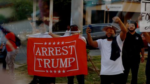 ATLANTA, GEORGIA - AUGUST 24: People look on as former U.S. President Donald Trump rides in a motorcade while travelling from the Fulton County jail on August 24, 2023 in Atlanta, Georgia. Trump surrendered at the Fulton County jail where he was booked on 13 charges related to an alleged plan to overturn the results of the 2020 presidential election in Georgia. (Photo by Joe Raedle/Getty Images)