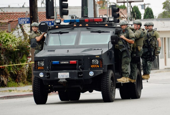 LOS ANGELES, CA - JUNE 25: Los Angeles County Sheriff's SWAT team members standing on a armored car arrive to help Los Angeles Police Department officers during a massive manhunt for a suspect who attempted to kill two detectives on June 25, 2013 in Los Angeles, California. The shooting happened in the early morning hours as the two detectives were ambushed and slightly injured outside the Los Angeles Police Department's Wilshire Station, prompting the closure of a 25-square-block area in the Mid-City section of Los Angeles. (Photo by Kevork Djansezian/Getty Images)