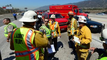 Los Angeles County Fire Department personel discuss matters on a closed California Foothill (210) Freeway on August 22, 2013 after a tour bus rolled off the road and overturned on the side of the freeway, closing the road as rescue personnel arrived on the scene. Some forty to fifty people were injured when the tour bus headed for a casino overturned during the busy morning commute, but according to Los Angeles County Fire Department dispatcher Kyle Sanford, there were no fatalities. The California News Servicde reported at least 10 ambulances responded to the scene, with at least three medical helicopters carrying patients to area hospitals. AFP PHOTO/Frederic J. BROWN (Photo credit should read FREDERIC J. BROWN/AFP via Getty Images)