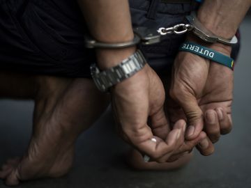 TOPSHOT - An alleged drug dealer is captured by policemen after a drug buy-bust operation on a slum area in Manila on September 28, 2017. Nearly half of Filipinos believe police are killing innocent people in waging President Rodrigo Duterte's anti-drugs war, according to survey results released Wednesday. / AFP PHOTO / NOEL CELIS (Photo credit should read NOEL CELIS/AFP via Getty Images)