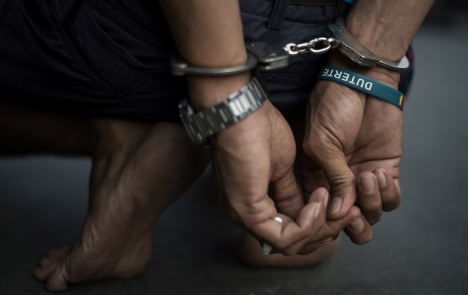 TOPSHOT - An alleged drug dealer is captured by policemen after a drug buy-bust operation on a slum area in Manila on September 28, 2017. Nearly half of Filipinos believe police are killing innocent people in waging President Rodrigo Duterte's anti-drugs war, according to survey results released Wednesday. / AFP PHOTO / NOEL CELIS (Photo credit should read NOEL CELIS/AFP via Getty Images)