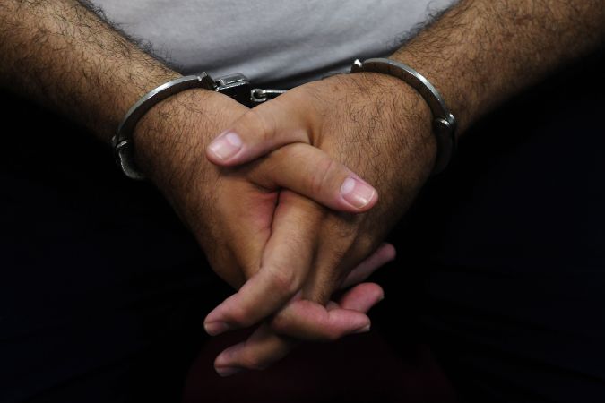 Detail of the hands of former Salvadoran President (2004-2009) Elias Antonio Saca with handcuffs, taken as he waits, along with six of his collaborators, for the judge to arrive in court in San Salvador on May 16, 2018, to face charges of embezzlement and laundering for allegedly diverting 298 million dollars. - Saca was arrested in October 2016 with his former private secretary and former communications secretary, among others, suspected of pocketing $246 million in public funds during his 2004-2009 mandate. They have been charged with embezzlement, criminal association and money laundering. (Photo by Marvin RECINOS / AFP) (Photo credit should read MARVIN RECINOS/AFP via Getty Images)