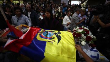 Simpatizantes colocan una bandera nacional sobre el féretro del candidato Fernando Villavicencio, durante un velatorio público en Quito.