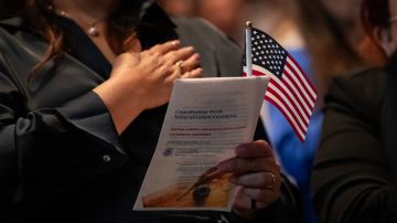 A new US citizen holds a small American flag as the national anthem is played during a US naturalization ceremony at the Los Angeles Central Library, in Los Angeles.