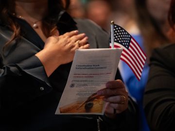 A new US citizen holds a small American flag as the national anthem is played during a US naturalization ceremony at the Los Angeles Central Library, in Los Angeles.