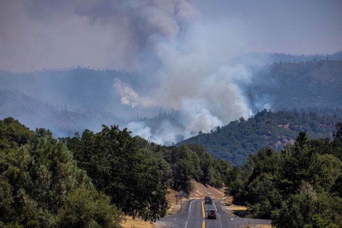 Smoke rises from the Oak Fire near Mariposa, California, on July 24, 2022. - The fierce California wildfire expanded early Sunday burning several thousand acres and forcing evacuations, as tens of millions of Americans sweltered through scorching heat with already record-setting temperatures due to climb even further. More than 2,000 firefighters backed by 17 helicopters have been deployed against the Oak Fire, which broke out Friday near Yosemite National Park, the California Department of Forestry and Fire Protection (CAL FIRE) said in a report. (Photo by DAVID MCNEW / AFP) (Photo by DAVID MCNEW/AFP via Getty Images)