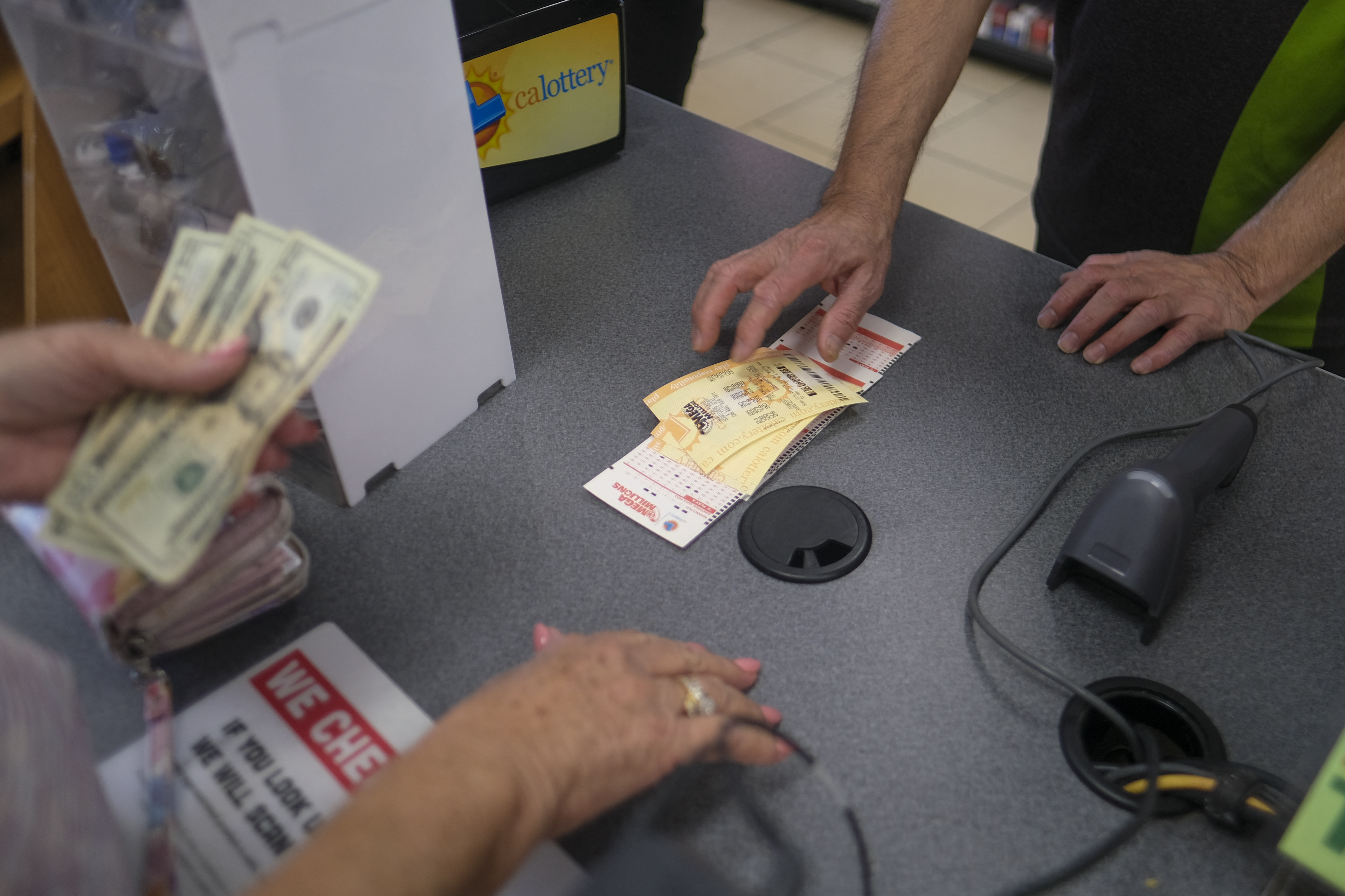 People buy their Mega Millions lottery tickets at a 7-Eleven convenience store in Chino Hills, California, July 28, 2022. - The odds of claiming this week's bonanza US lottery prize are less than one-in-300-million -- but one "lucky" convenience store outside Los Angeles is already counting its winnings. A sign above the counter of the otherwise unassuming shop in California's Chino Hills proclaims itself the "LUCKIEST 7-ELEVEN IN THE WORLD," six years after it sold a winning ticket for the largest jackpot in US lottery history. (Photo by RINGO CHIU / AFP) (Photo by RINGO CHIU/AFP via Getty Images)