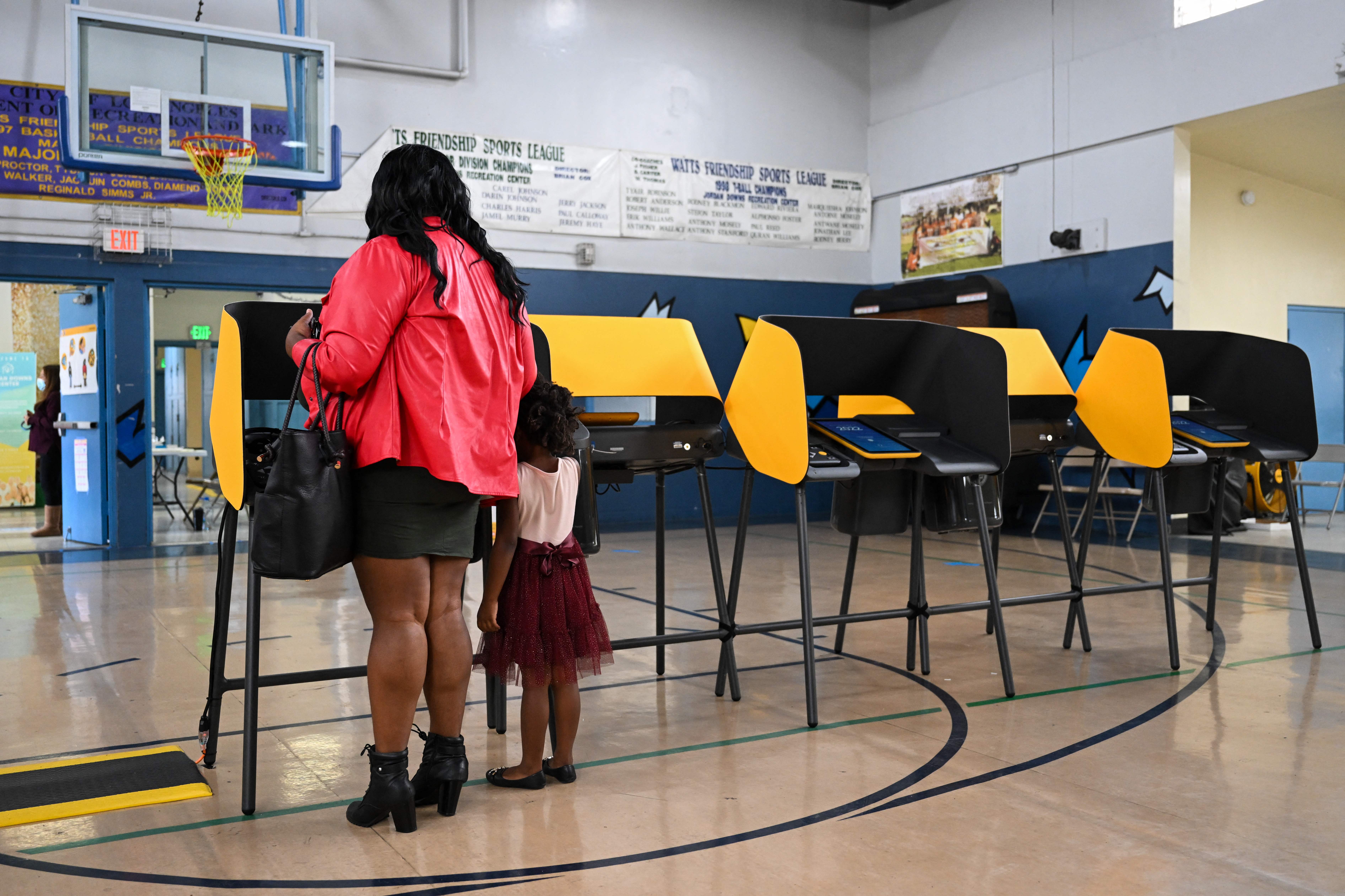 A person votes with a young child in US midterm elections inside a vote center at the Jordan Downs Recreation Center in Los Angeles, California on November 8, 2022. (Photo by Patrick T. FALLON / AFP) (Photo by PATRICK T. FALLON/AFP via Getty Images)