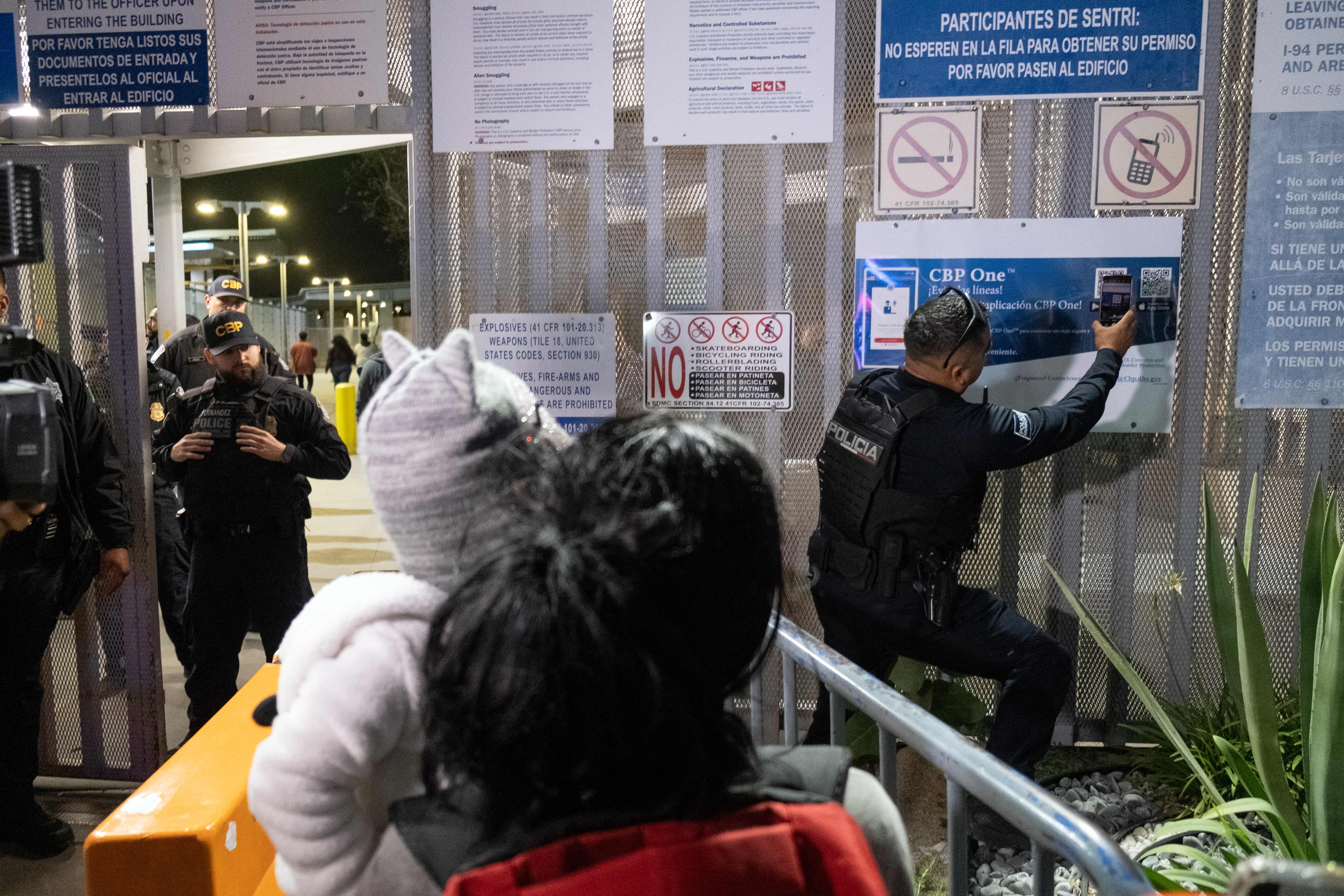 Un policía de México escanea la aplicación de asilo en CBP One de un inmigrante, antes de autorizar su paso a EE.UU.