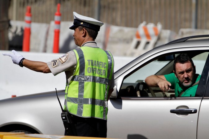 LOS ANGELES, CA - SEPTEMBER 29: A Los Angeles traffic officer assists a driver at the road closure where construction crews are demolishing a portion of the Mulholland Drive bridge that spans the 405 Freeway September 29, 2012 in Los Angeles, California. The 405 Freeway is completely shut down for a 10 mile stretch this weekend for the demolition that is part of a larger $1-billion freeway improvement project. (Photo by Jonathan Alcorn/Getty Images)