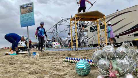 Attendees known as "burners" strike down their Unicorner camp before new rainfalls in a muddy desert plain on September 3, 2023, after heavy rains turned the annual Burning Man festival site in Nevada's Black Rock desert into a mud pit. Tens of thousands of festivalgoers were stranded September 3, in deep mud in the Nevada desert after rain turned the annual Burning Man gathering into a quagmire, with police investigating one death. Video footage showed costume-wearing "burners" struggling across the wet gray-brown site, some using trash bags as makeshift boots, while many vehicles were stuck in the sludge. (Photo by Julie JAMMOT / AFP) (Photo by JULIE JAMMOT/AFP via Getty Images)