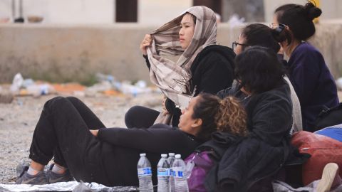 Mujeres inmigrantes descansan entre vallas de la frontera entre México y Estados Unidos en San Diego, California.