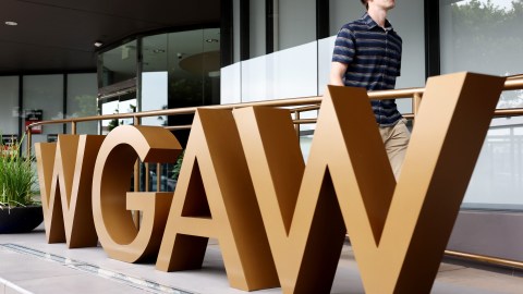 LOS ANGELES, CALIFORNIA - SEPTEMBER 25: A person walks past the WGAW logo displayed outside Writers Guild of America West headquarters on September 25, 2023 in Los Angeles, California. Hollywood is awaiting the final vote on a tentative contract agreement between over 11,000 Writers Guild of America members and Hollywood studios in the nearly 150-day writers strike. (Photo by Mario Tama/Getty Images)