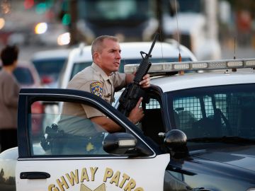 SAN BERNARDINO, CA - DECEMBER 02: A California Highway Patrol officer stands with his weapon as authorities pursued the suspects in a shooting that occurred at the Inland Regional Center on December 2, 2015 in San Bernardino, California. Police continue to search for suspects in the shooting that left at least 14 people dead and another 17 injured. (Photo by Sean M. Haffey/Getty Images)