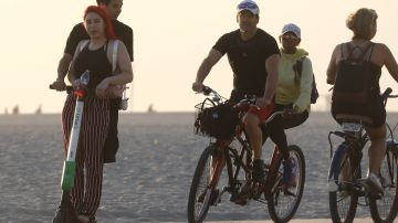 LOS ANGELES, CA - AUGUST 13: A man and woman (L) ride a shared dockless electric scooter next to bicycles along Venice Beach on August 13, 2018 in Los Angeles, California. Shared e-scooter startups Bird and Lime have rapidly expanded in the city. Some city residents complain the controversial e-scooters are dangerous for pedestrians and sometimes clog sidewalks. A Los Angeles Councilmember has proposed a ban on the scooters until regulations can be worked out. (Photo by Mario Tama/Getty Images)