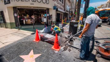 Workers clean up a "Walk of Fame" star outside a tourist store on Hollywood Blvd, Hollywood, California on June 12, 2020. - California will allow film, television and music production to resume from June 12 if conditions permit after months of lockdown due to the coronavirus pandemic, the governor's office said Friday. (Photo by Mark RALSTON / AFP) (Photo by MARK RALSTON/AFP via Getty Images)
