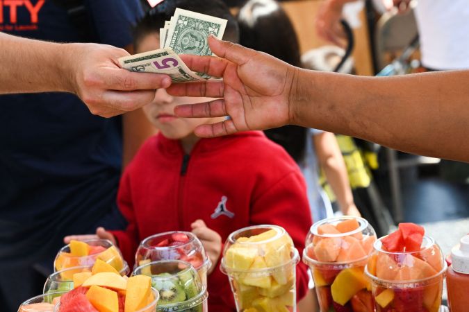 A customer pays cash for a container of fresh fruit from a street vendor along Hollywood Blvd on July 13, 2022 in Los Angeles, California. - US consumer price inflation surged 9.1 percent over the past 12 months to June, the fastest increase since November 1981, according to government data released on July 13. Driven by record-high gasoline prices, the consumer price index jumped 1.3 percent in June, the Labor Department reported. (Photo by Patrick T. FALLON / AFP) (Photo by PATRICK T. FALLON/AFP via Getty Images)