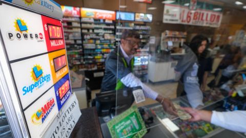 People buy their Mega Millions lottery tickets at a 7-Eleven convenience store in Chino Hills, California, July 28, 2022. - The odds of claiming this week's bonanza US lottery prize are less than one-in-300-million -- but one "lucky" convenience store outside Los Angeles is already counting its winnings. A sign above the counter of the otherwise unassuming shop in California's Chino Hills proclaims itself the "LUCKIEST 7-ELEVEN IN THE WORLD," six years after it sold a winning ticket for the largest jackpot in US lottery history. (Photo by RINGO CHIU / AFP) (Photo by RINGO CHIU/AFP via Getty Images)