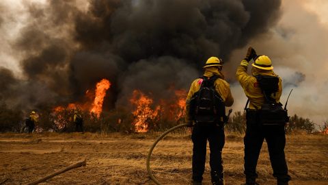 CalFire firefighters pull a hose line as others use drip torches during a firing operation to build a line to contain the Fairview Fire near Hemet, California, on September 8, 2022. - A ferocious heat wave scorching the western United States could finally begin to wane in the coming days, forecasters said on September 7, but they warned of dangerous fire conditions as howling winds sweep through the bone-dry region. (Photo by Patrick T. FALLON / AFP) (Photo by PATRICK T. FALLON/AFP via Getty Images)