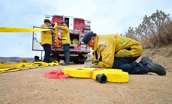 Firefighters prepare hoses to fight the Fairview Fire inside the San Bernardino National Forest near Hemet, California on September 9, 2022. - The wildfire burning outside Los Angeles has doubled in size in less than 24 hours, firefighters said on September 8 as they endured yet another day of blistering heat in the western US. Thousands of people have been told to evacuate in the face of the growing fire, which has now spread to 19,000 acres (7,700 hectares). (Photo by Frederic J. BROWN / AFP) (Photo by FREDERIC J. BROWN/AFP via Getty Images)