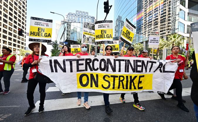 Hotel workers on strike hold placards outside the InterContinental Hotel in downtown Los Angeles, California on August 7, 2023. Hundreds of hotel workers in Southern California walked off the job on Monday, demanding higher pay and better benefits. (Photo by Frederic J. BROWN / AFP) (Photo by FREDERIC J. BROWN/AFP via Getty Images)