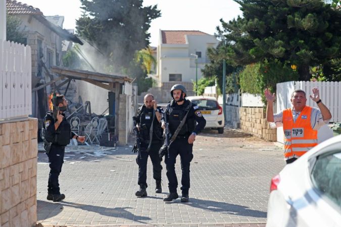 Miembros de las fuerzas de seguridad de Israel y equipos de rescate reaccionan durante el bombardeo en Ashkelon mientras se lanzan salvas de cohetes desde la Franja de Gaza hacia Israel.