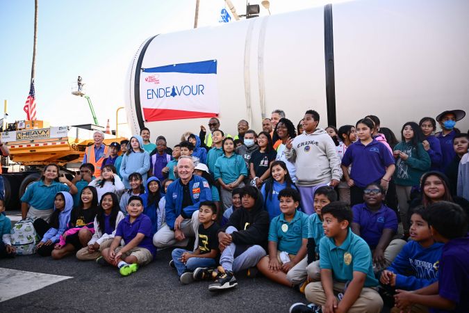 Astronaut Doug Hurley stands for photos with a group of students as the Space Shuttle Solid Rocket Motors (SRM) are transported down Figueroa Street to the California Science Center to complete the Solid Rocket Booster and be stacked in a vertical display with NASA's Space Shuttle Endeavour and external fuel tank in Los Angeles, California on October 11, 2023. The California Science Center announced the "Go for Stack," six-month process of moving and lifting each of the space shuttle components into place for vertical display at the center. (Photo by Patrick T. Fallon / AFP) (Photo by PATRICK T. FALLON/AFP via Getty Images)