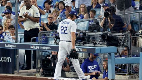 Clayton Kershaw sale del juego en el primer inning recibiendo apoyo de Magic Johnson (izq.), codueño de los Dodgers.