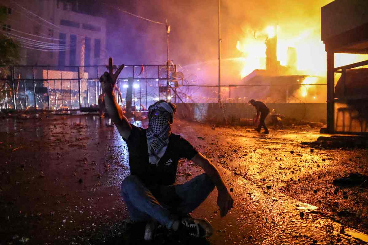 Un manifestante muestra la V de la victoria ante el incendio cerca de la puerta de seguridad de la embajada de Estados Unidos en Líbano.