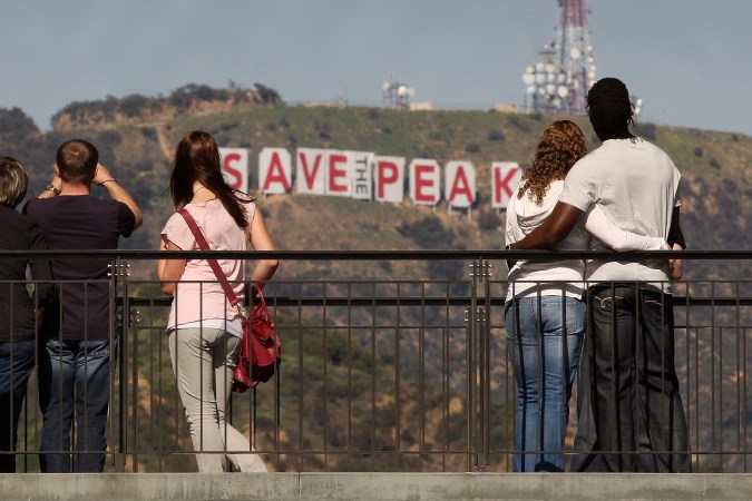 LOS ANGELES, CA - FEBRUARY 13: Visitors to the Hollywood and Highland complex view the iconic 450-foot-long Hollywood sign after activists covered it with banners during an effort to prevent the building of houses there on February 13, 2010 in Los Angeles, California. The Trust for Public Land is draped the sign in cooperation with city council member Tom LaBonge as it campaigns to raise enough funds to buy Cahuenga Peak and stop developers from purchasing the 138-acre parcel to build mansions around the Hollywood sign. A group of Chicago investors that bought the property from the estate of aircraft titan Howard Hughes in 2002 announced that they plan to subdivide the peak into luxury home sites. The land trust has raised about half the $12.5 million needed to buy the peak. They need to raise the rest by April 14. (Photo by David McNew/Getty Images)