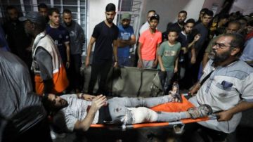 Un hombre herido es llevado en camilla después del ataque al hospital Bautista Al-Ahli.