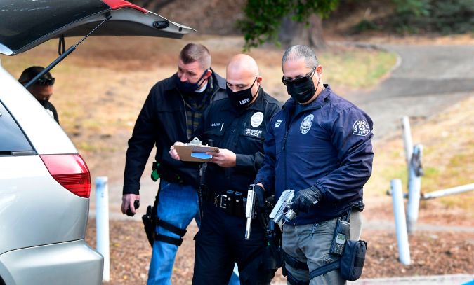Los Angeles Police Department officers recover guns from the back of vehicles as residents turn in firearms at a "Gun Buy Back" event in Los Angeles, California on December 5, 2020. - The "Gun Buy Back" program is used by the LAPD to help reduce gun violence, improve security in communities and those participating can anonymously turn in firearms in exhange for giftcards valued at $100 for handguns, shotguns and rifles and $200 for assault weapons, as classified by the state of California. (Photo by Frederic J. BROWN / AFP) (Photo by FREDERIC J. BROWN/AFP via Getty Images)