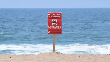 A sign indicates that the Dockweiler State Beach is closed to swimming after a sewage spill in Playa del Rey, in Los Angeles County, California, on July 13, 2021. - 17 million gallons of sewage were discharged from the Hyperion Water Reclamation Plant one mile offshore, instead of the usual five miles, after the plant was "inundated with overwhelming quantities of debris", according to a statement released by LA Sanitation and Environment on July 12, 2021. (Photo by FREDERIC J. BROWN / AFP) (Photo by FREDERIC J. BROWN/AFP via Getty Images)