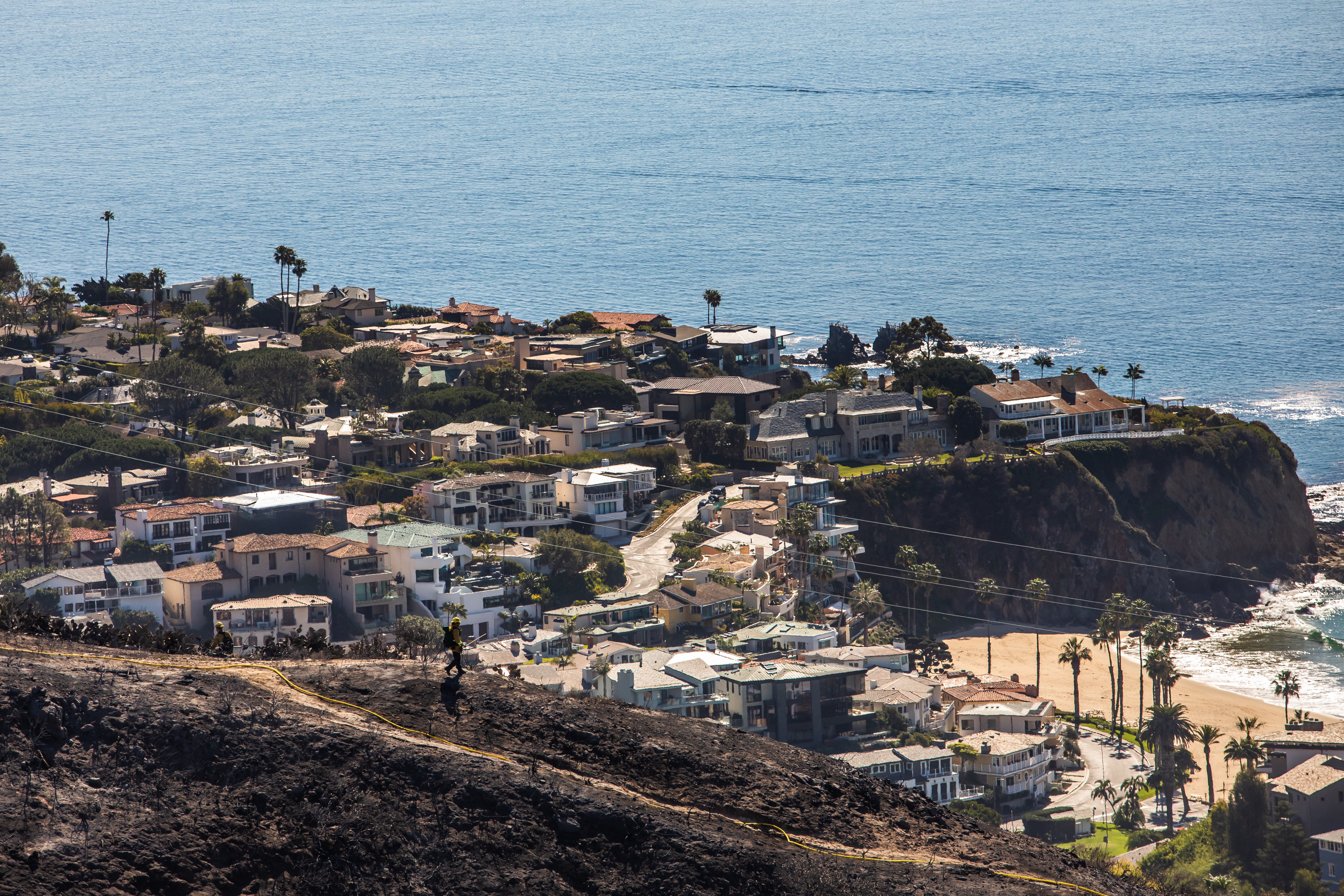 LAGUNA BEACH, CA - FEBRUARY 10: A firefighter monitors the situation on a smoldering hillside in Laguna Beach, California on February 10, 2022. A wind-driven brush fire that broke out in the hills near Laguna Beach amid high temperatures and low humidity forced residents to flee their homes early February 10, 2022. (Photo by Apu Gomes/Getty Images)