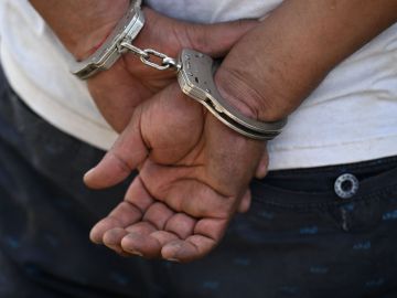 A man remains handcuffed after being detained by the police during an operation against gang members in Soyapango, El Salvador, on December 3, 2022. - Around 10,000 Salvadoran army troops and police officers surrounded the populous city of Soyapango, on the outskirts of capital San Salvador, as the government stepped up its fight against criminal gangs, President Nayib Bukele announced Saturday. (Photo by Marvin RECINOS / AFP) (Photo by MARVIN RECINOS/AFP via Getty Images)