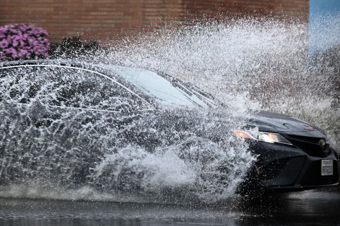 A car drives in the rain through storm water during a winter storm Los Angeles, California, on March 14, 2023. (Photo by Patrick T. Fallon / AFP) (Photo by PATRICK T. FALLON/AFP via Getty Images)