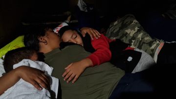 Dasling Sanchez, 28, holds her sleeping sons as they rest next to a gas station in downtown Brownsville, Texas, on May 6, 2023. Sanchez is waiting for her brother, who lives in Los Angeles, California, to buy them bus tickets to continue their trip into the US to meet him. - Migrants crossed the Rio Grande and surrendered to Customs and Border Patrol agents a few days ago. Then they were taken to a detention center and released on American soil, where they are free to remain while a migration judge reviews their cases. Some of them are waiting for another relative to be released to continue on their way, and others are waiting for a relative that lives in the United States to buy their tickets to continue their trips. Humanitarian organizations say that there was an important increase in migrants in the last month, from 200 to 700 daily, because they are afraid that after the end of Title 42, they could be deported to their original countries or banned to enter the US for several years. (Photo by Moisés ÁVILA / AFP) (Photo by MOISES AVILA/AFP via Getty Images)