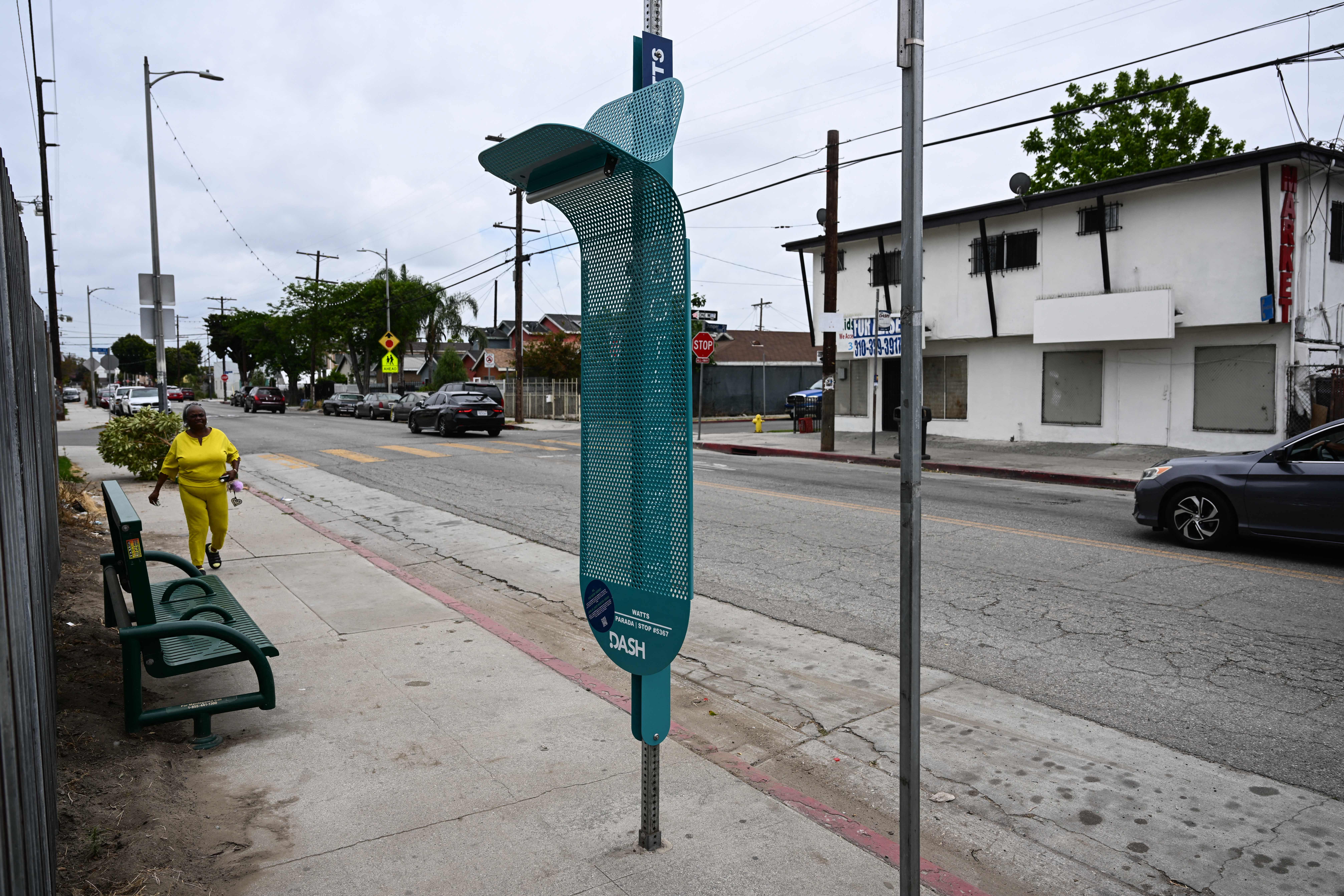 A pedestrian walks past La Sombrita, a prototype bus stop structure to provide shade during the day and solar-powered lighting at night installed by the Los Angeles Department of Transportation (LADOT) as a grant-funded pilot project for bus transit patrons, stands in the Watts neighborhood of Los Angeles, California on May 25, 2023. (Photo by Patrick T. Fallon / AFP) (Photo by PATRICK T. FALLON/AFP via Getty Images)