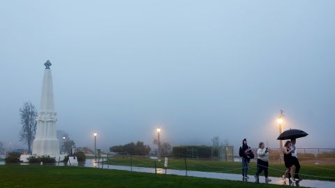 LOS ANGELES, CALIFORNIA - FEBRUARY 24: A couple walks to take photos amid the rain and fog at Griffith Observatory on February 24, 2023 in Los Angeles, California. A major storm, carrying a rare blizzard warning for parts of Southern California, has begun to deliver heavy snowfall to the mountains with some snowfall expected to reach lower elevations in Los Angeles County. (Photo by Mario Tama/Getty Images)