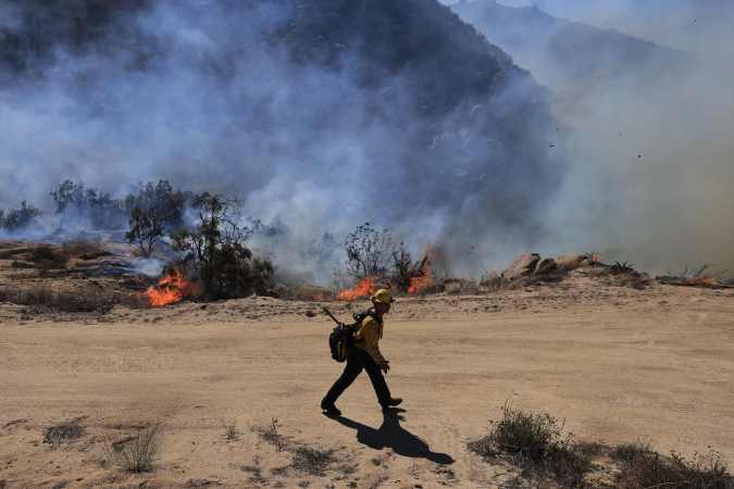 A firefighter walks toward flames as the Highland Fire burns in Aguana, California, on October 31, 2023. Thousands of people were being told to flee a wildfire spreading in southern California on October 31, as strong winds fanned the flames. Around 5,700 people were urged to leave areas threatened by the blaze, which erupted on October 30 around lunchtime and had engulfed 2,200 acres (900 hectares) by the following morning. (Photo by DAVID SWANSON / AFP) (Photo by DAVID SWANSON/AFP via Getty Images)