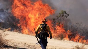 TOPSHOT - A firefighter walks toward flames as the Highland Fire burns in Aguana, California, on October 31, 2023. Thousands of people were being told to flee a wildfire spreading in southern California on October 31, as strong winds fanned the flames. Around 5,700 people were urged to leave areas threatened by the blaze, which erupted on October 30 around lunchtime and had engulfed 2,200 acres (900 hectares) by the following morning. (Photo by DAVID SWANSON / AFP) (Photo by DAVID SWANSON/AFP via Getty Images)