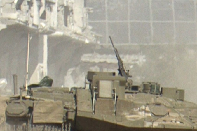 Una captura de un video de AFPTV muestra un vehículo blindado israelí pasando junto a palestinos que huyen de la ciudad de Gaza.