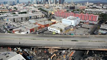 LOS ANGELES, CALIFORNIA - NOVEMBER 13: An aerial view of cleanup crews working (BOTTOM) beneath the closed I-10 freeway following a large pallet fire, which occurred past Saturday at a storage yard, on November 13, 2023 in Los Angeles, California. Engineers have been assessing the extent of the damage and it remains unknown how long the freeway, which is a major commuter artery through the downtown area, will remain closed and complicate traffic for the city. California Gov. Gavin Newsom said that over 300,000 vehicles drive through the freeway corridor each day and drivers are being urged to use public transit. (Photo by Mario Tama/Getty Images)