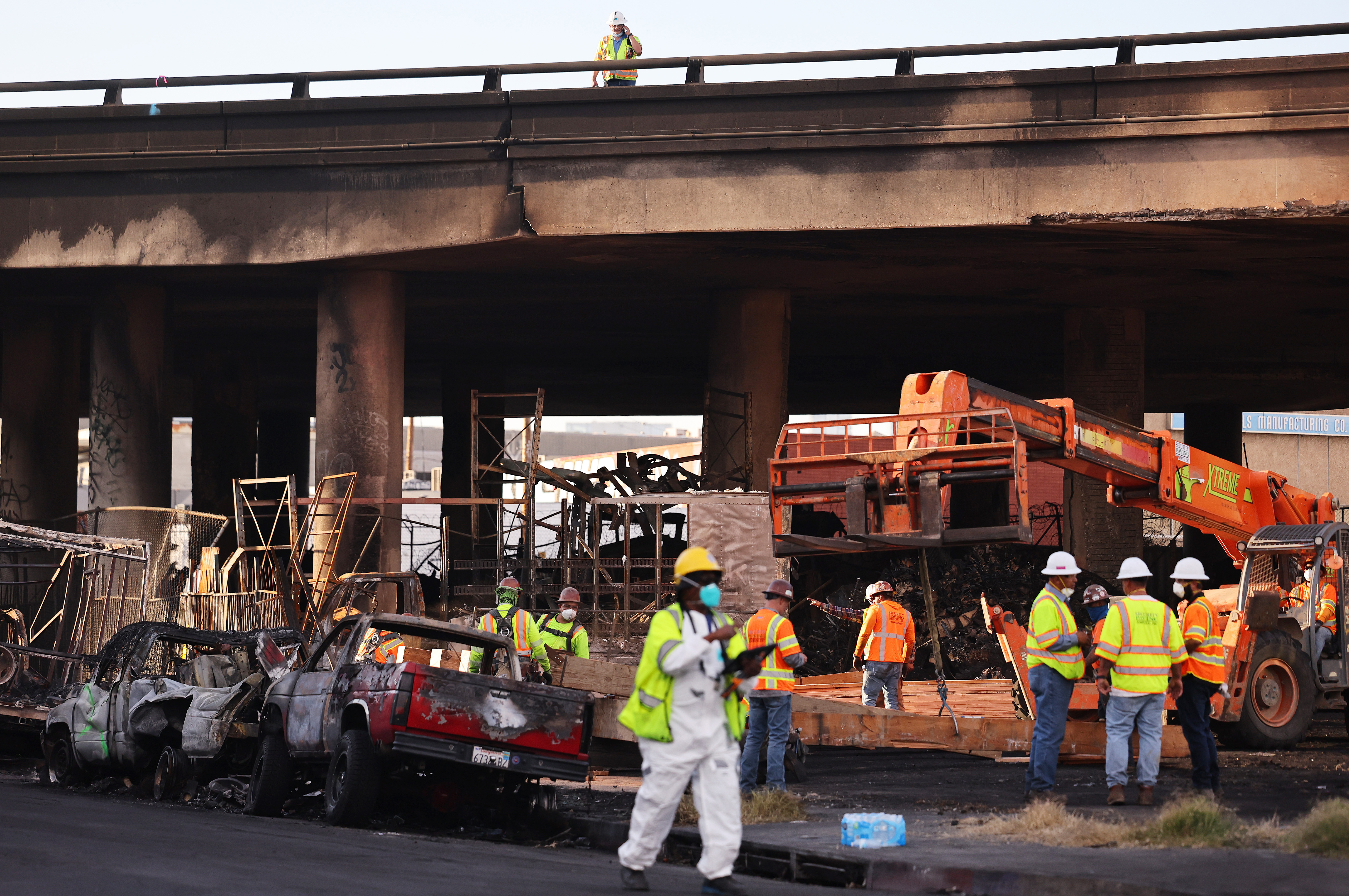 LOS ANGELES, CALIFORNIA - NOVEMBER 13: Crews work beneath the closed I-10 elevated freeway following a large pallet fire, which occurred Saturday at a storage yard beneath the freeway, on November 13, 2023 in Los Angeles, California. Engineers have been assessing the extent of the damage and it remains unknown how long the freeway, which is a major commuter artery through the downtown area, will remain closed and complicate traffic for the city. California Governor Gavin Newsom said the fire was caused by arson and that over 300,000 vehicles drive through the freeway corridor each day with drivers being urged to use public transit. (Photo by Mario Tama/Getty Images)