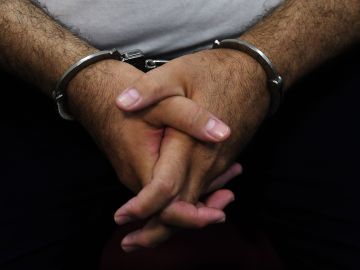 Detail of the hands of former Salvadoran President (2004-2009) Elias Antonio Saca with handcuffs, taken as he waits, along with six of his collaborators, for the judge to arrive in court in San Salvador on May 16, 2018, to face charges of embezzlement and laundering for allegedly diverting 298 million dollars. - Saca was arrested in October 2016 with his former private secretary and former communications secretary, among others, suspected of pocketing $246 million in public funds during his 2004-2009 mandate. They have been charged with embezzlement, criminal association and money laundering. (Photo by Marvin RECINOS / AFP) (Photo credit should read MARVIN RECINOS/AFP via Getty Images)