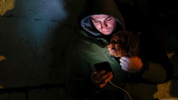 Un habitante de Kiev revisa el celular mientras carga a su mascota en un refugio antiaéreo durante el tiempo de alarma por ataques aéreos rusos contra la ciudad.